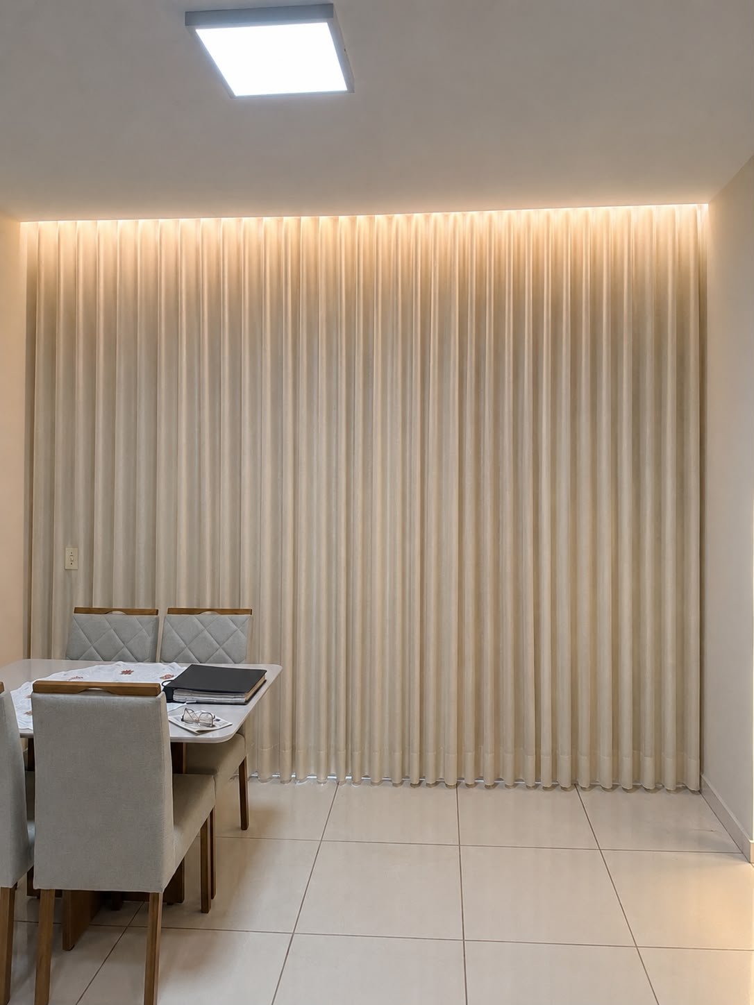 Cortina wave em tecido claro instalada em sala de jantar com iluminação embutida